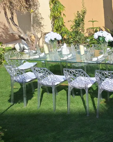 طاولة زجاجية بكراسي شفافة على العشب