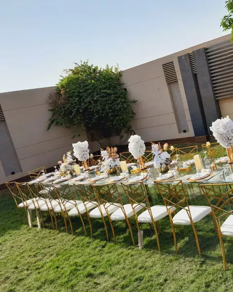 طاولة طويلة بكراسي بيضاء وذهبية على العشب