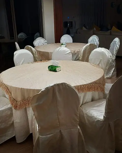 طاولة دائرية بمفرش كريمي وكراسي مغطّاة
