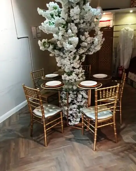 طاولة صغيرة بكراسي ذهبية وزهور بيضاء