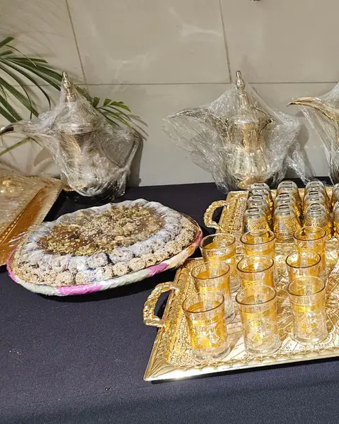 أكواب شاي ذهبية وحلويات على طاولة سوداء