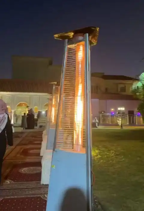 مدفأة خارجية مضاءة على عشب الحديقة ليلاً