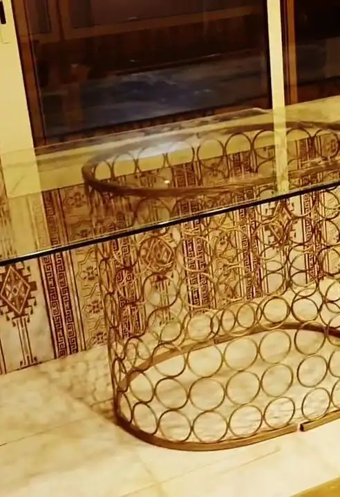 طاولة زجاجية مستديرة بقاعدة ذهبية من حلقات متداخلة