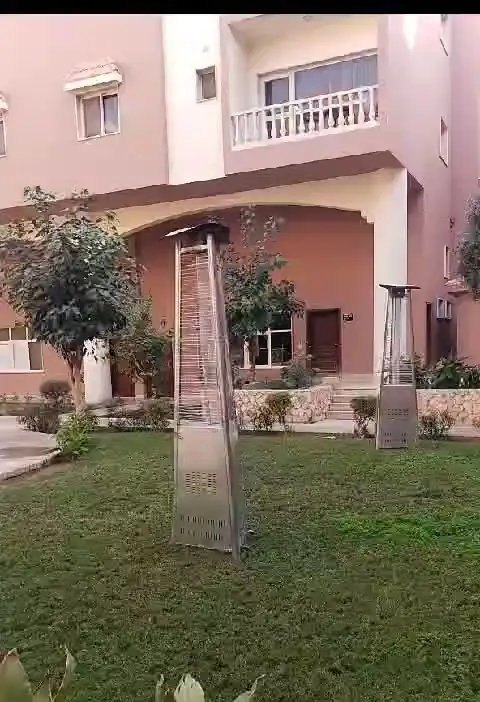 مدفأة خارجية على العشب أمام مبنى سكني