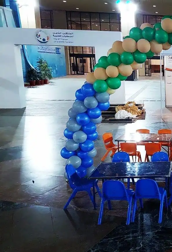 طاولات وكراسي ملونة للأطفال تحت قوس من البالونات في معرض