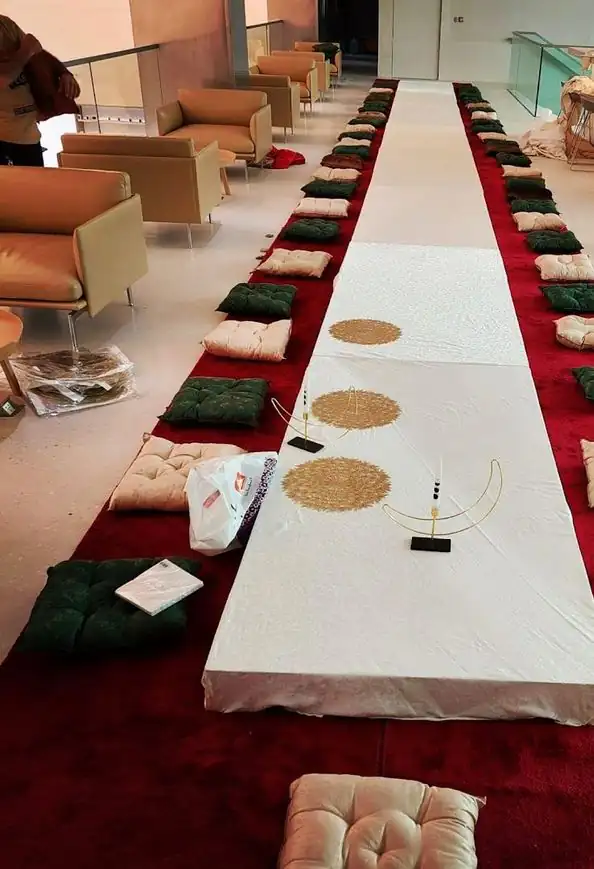 طاولة منخفضة طويلة وحولها وسائد خضراء فوق سجاد أحمر