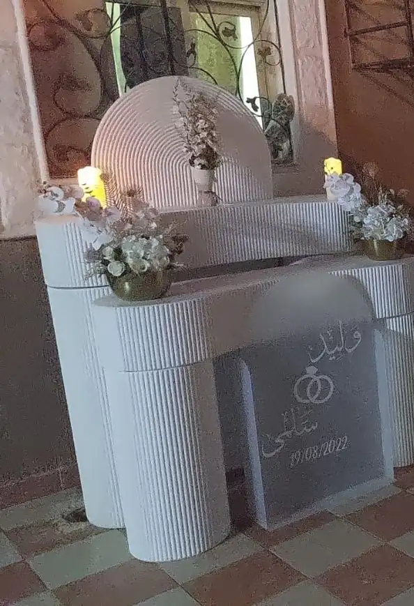 طاولة استقبال بيضاء مع شموع وزهور وقاعدة عرض مدرجة