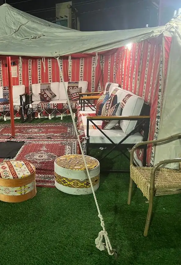 مظلة خضراء فوق جلسة بسجاد أحمر على عشب صناعي