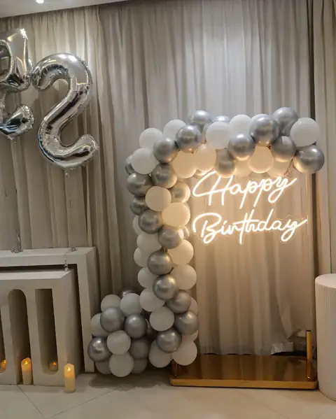 A birthday corner with silver balloons and a neon sign