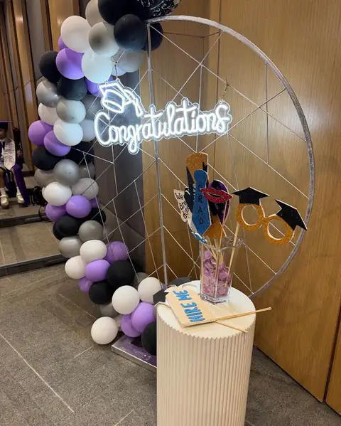 A graduation entrance with balloons, a round frame and a neon sign
