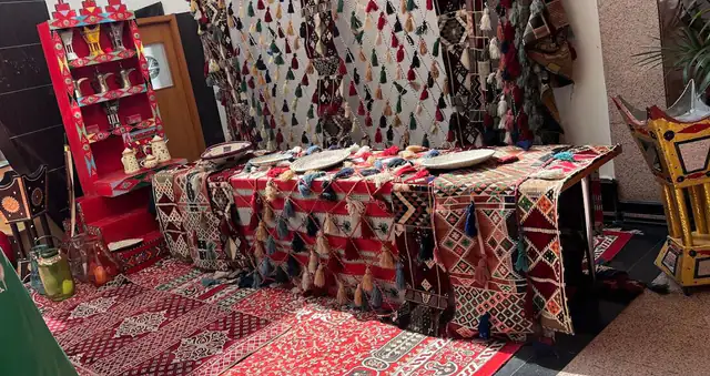 A traditional sitting with red heritage rugs and cushions