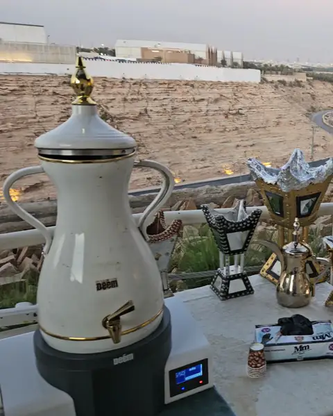 A hospitality corner with coffee urns and cups on a table overlooking the road