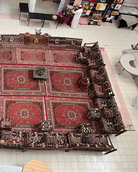 مشهد علوي لمجلس مرتب على سجاد أحمر فوق أرضية بلاط
