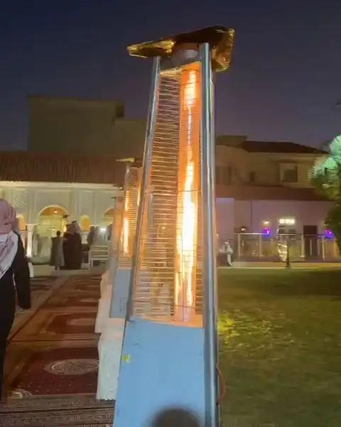 مدفأة خارجية مضاءة على عشب الحديقة ليلاً