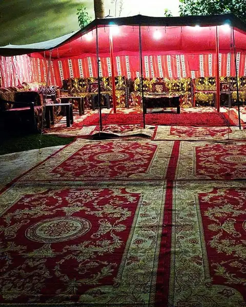 خيمة بإضاءة حمراء فوق سجاد أحمر في المساء