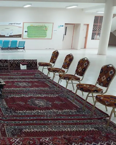 قاعة فسيحة فرشت بسجاد أحمر مع جلسات أرضية وكراسي مزخرفة