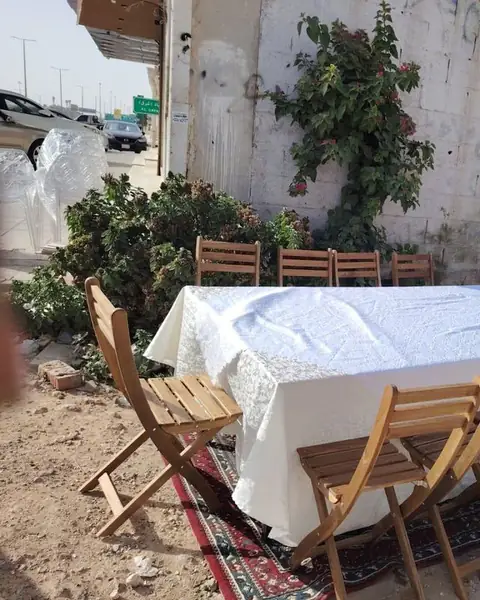 كراسي خشبية قابلة للطي حول طاولة بمفرش أبيض فوق سجاد في الهواء الطلق