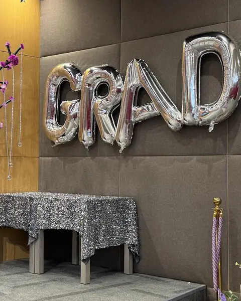 بالونات فضية على شكل كلمة GRAD وطاولة بقماش لامع وشجرة زينة