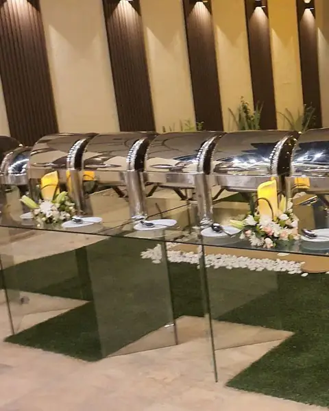 صف من أواني التقديم الحافظة للحرارة على منصة زجاجية بجانب مسبح