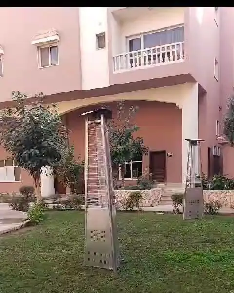 مدفأة خارجية على العشب أمام مبنى سكني