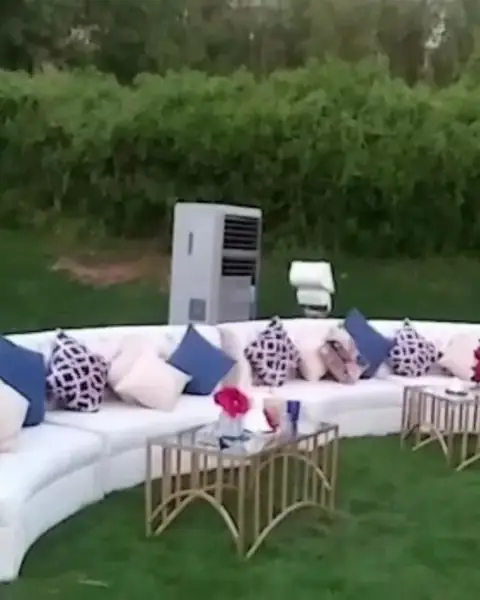 وحدة تبريد بيضاء قائمة خلف أريكة بيضاء منحنية على العشب