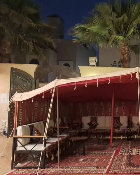 خيمة بداخلها بطانة حمراء فوق جلسة مجلس عند الغروب