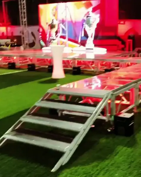 منصة مرتفعة بدرج فوق عشب صناعي وشاشة عرض خلفها